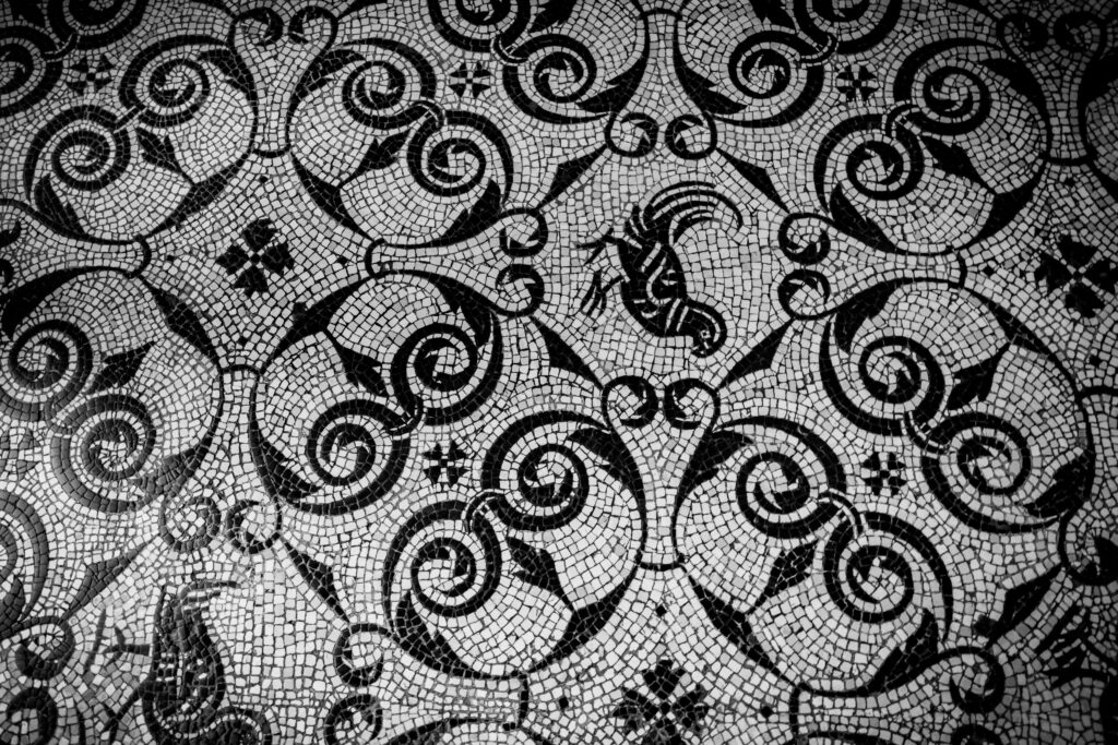 Detailed black and white mosaic floor capturing ancient Roman art with intricate patterns and designs.